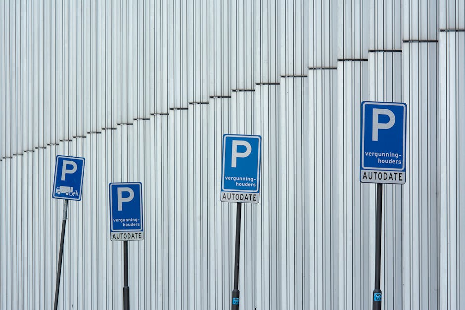 Four blue parking permit signs attached to metal poles are positioned along a corrugated metal wall, with each sign indicating parking permissions and autodata validation. The signs display a large white 'P' for parking, accompanied by smaller text in Dutch, including 'vergunning-houders' and 'AUTODATE.' The signs are arranged from left to right at varying heights. The background wall is made of vertical silver metal panels, creating an industrial setting. This image captures the context of parking regulation signage, which may be relevant for house removals and moving logistics, as parking permits are often essential when planning a home relocation or furniture transport in Cranham, as referenced in the page about Havering Council parking permits for Cranham removals by Man with Van Cranham.